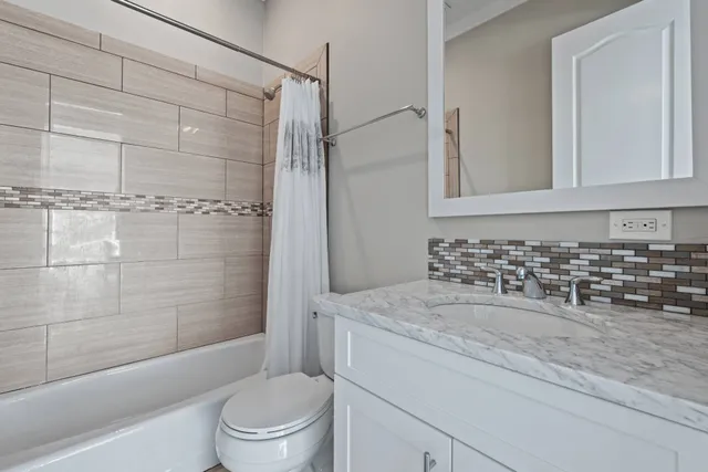 a bathroom with a granite countertop bathtub shower sink vanity and toilet