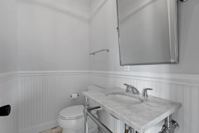a bathroom with a granite countertop toilet sink and mirror