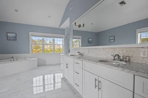 a spacious bathroom with double vanity sink a bathtub and mirror