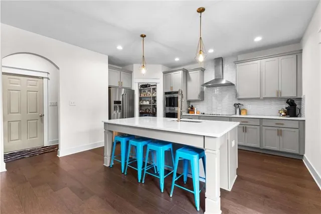 a kitchen with stainless steel appliances granite countertop a sink a stove a refrigerator and island with wooden floor