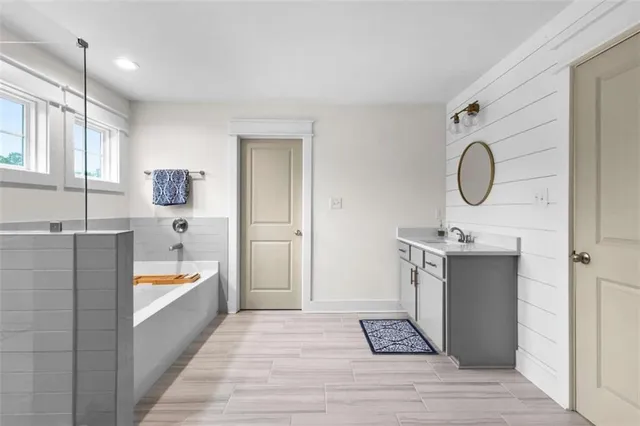 a bathroom with a tub sink and mirror