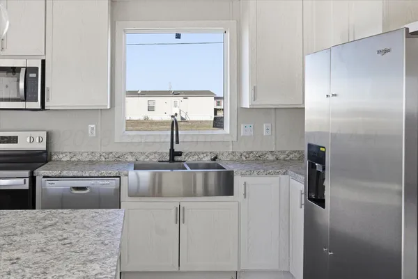 a kitchen with stainless steel appliances granite countertop a sink and a refrigerator