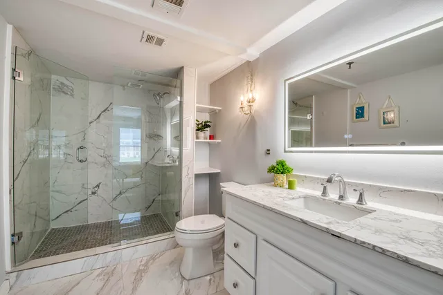 a bathroom with a granite countertop sink toilet and shower
