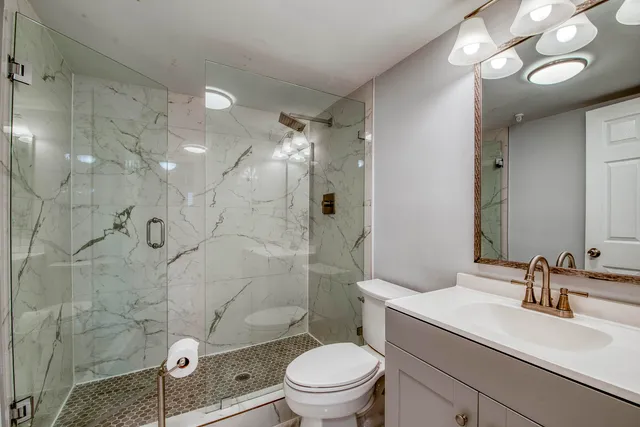 a bathroom with a sink a toilet a mirror and shower