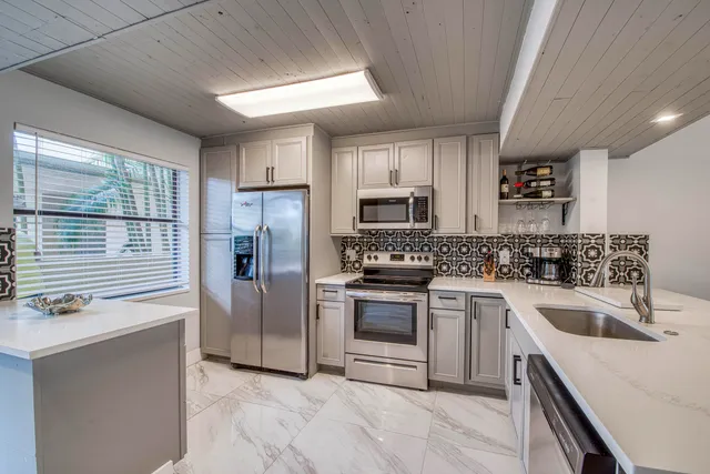 a kitchen with a sink white cabinets and stainless steel appliances