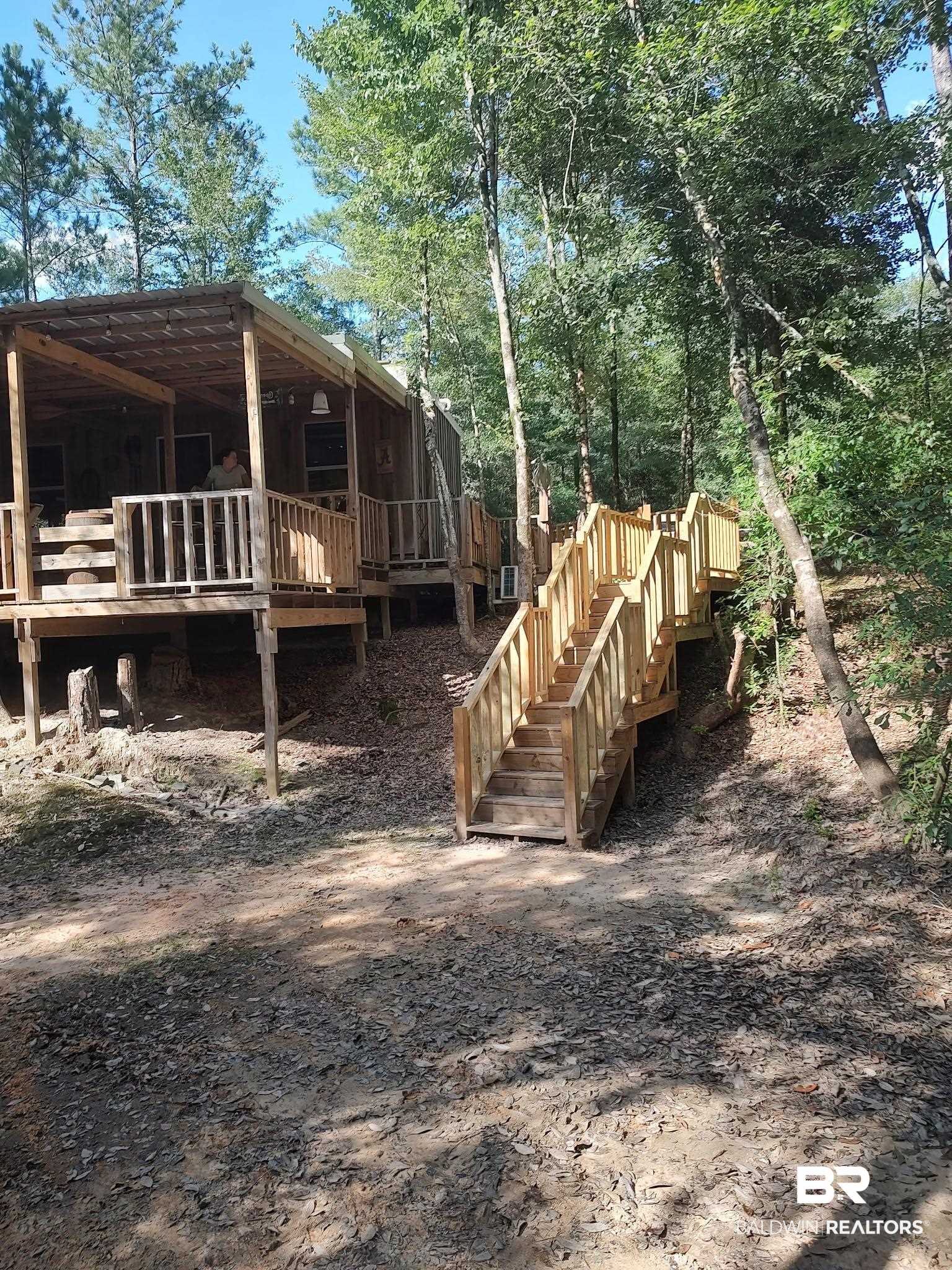 1 Mason Ferry Road Citronelle, AL 36522 - Photo 40 of 40 Wood-sided cabin featuring a covered wood-framed porch, a wood deck, a wood staircase with railings, and mature trees providing natural shade