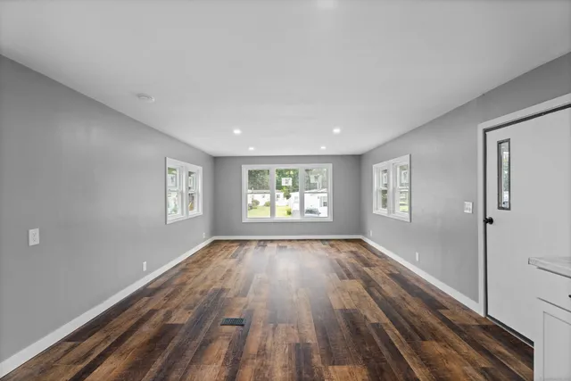 a view of an empty room and a window and wooden floor