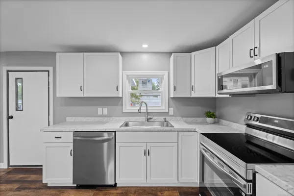 a kitchen with white cabinets stainless steel appliances a sink and a stove