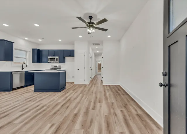 a large kitchen with stainless steel appliances granite countertop a sink dishwasher stove and a refrigerator with wooden floor