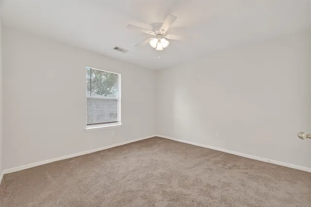 an empty room with a chandelier fan and windows
