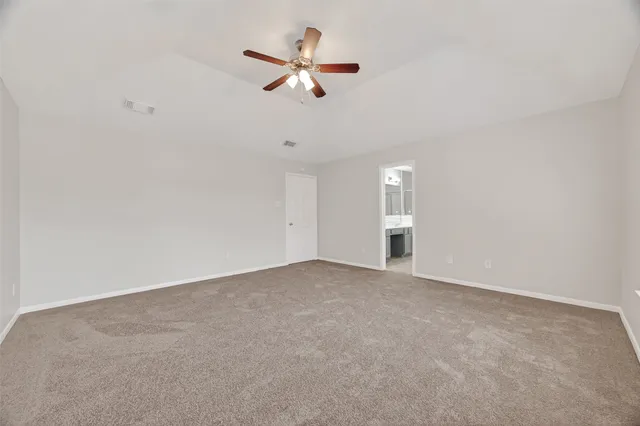 an empty room with ceiling fan and window