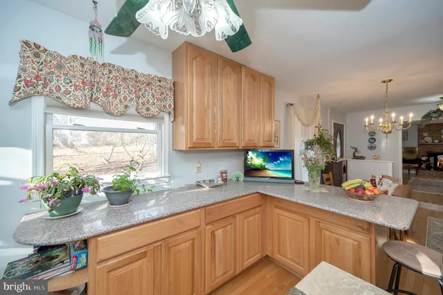 a kitchen with stainless steel appliances a sink a table a chandelier and cabinets