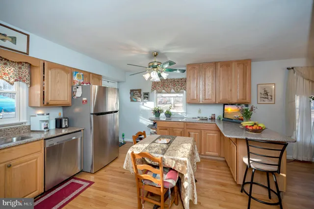 a kitchen with stainless steel appliances a dining table chairs refrigerator and sink