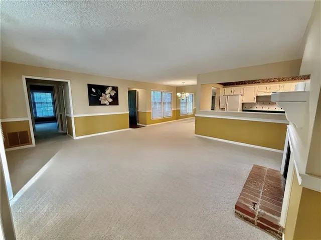 a view of an empty room with a window and a kitchen