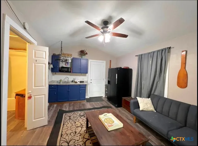 a living room with stainless steel appliances kitchen island granite countertop furniture and a rug