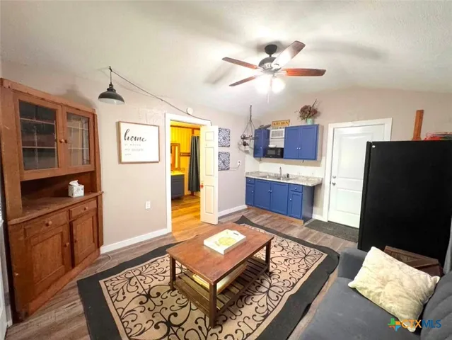 a living room with stainless steel appliances furniture a rug and a window
