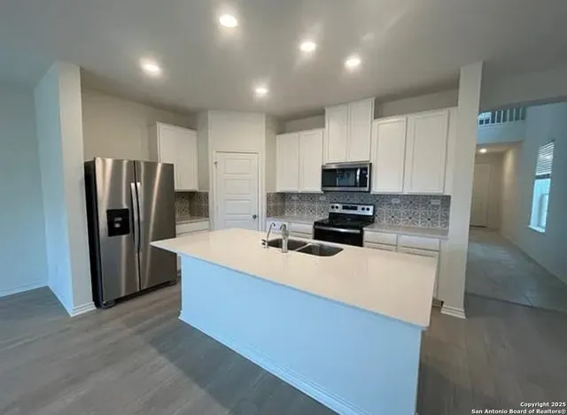 a kitchen with stainless steel appliances granite countertop a refrigerator a stove a sink and a microwave