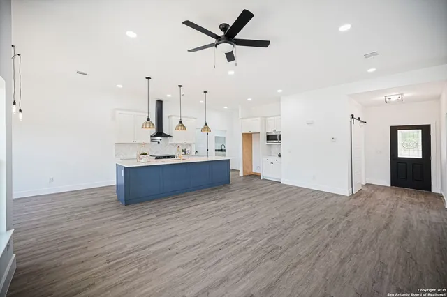 a kitchen with a sink dishwasher a stove a kitchen island with wooden floor and cabinets