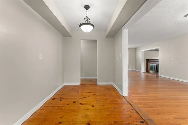 a view of an empty room with window and wooden floor