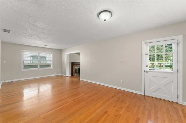 an empty room with wooden floor and windows