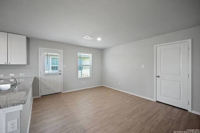 a view of an empty room with a window and wooden floor