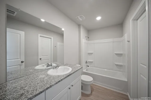 a bathroom with a granite countertop sink toilet and shower