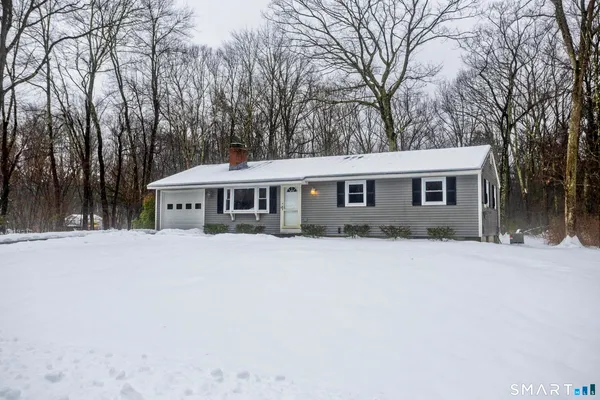 a front view of a house with a yard covered in snow