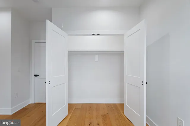 a view of a hallway with wooden floor and closet