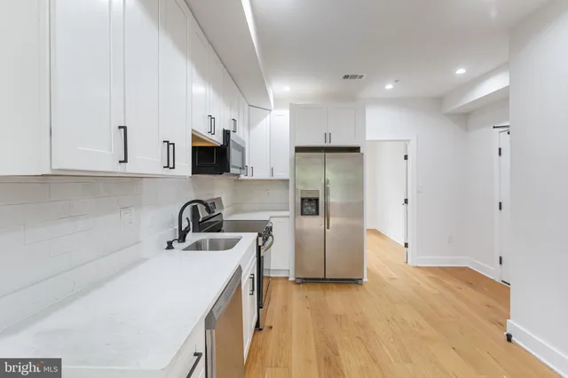 a kitchen with a sink a refrigerator and cabinets