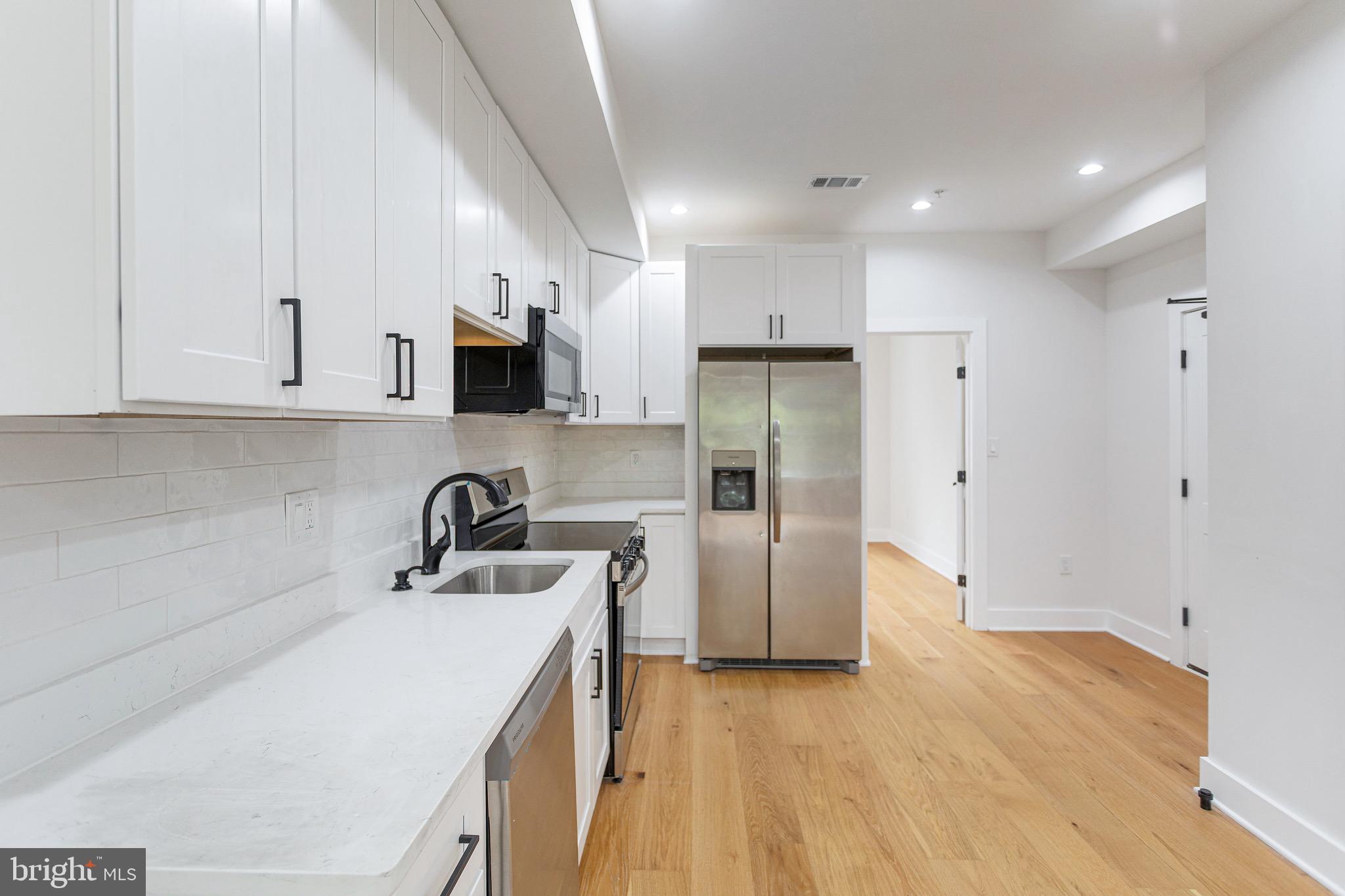 1107 Queen Street Northeast, Unit PH4 Washington, DC 20002 - Photo 2 of 28 a kitchen with a sink a refrigerator and cabinets