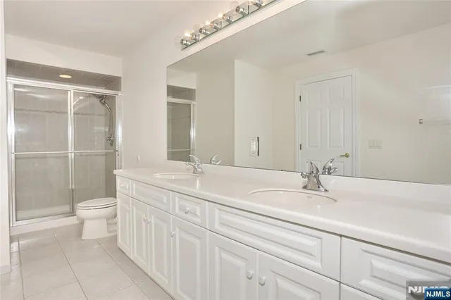 a bathroom with a double vanity sink toilet and shower