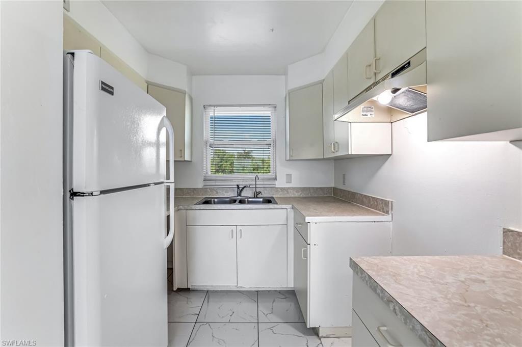 1000 Manatee Road, Unit A306 Naples, FL 34114 - Photo 3 of 13 a kitchen with a sink a refrigerator and a stove