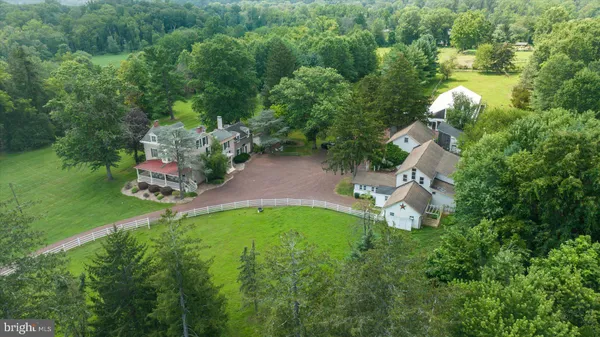 an aerial view of residential house with outdoor space and trees all around