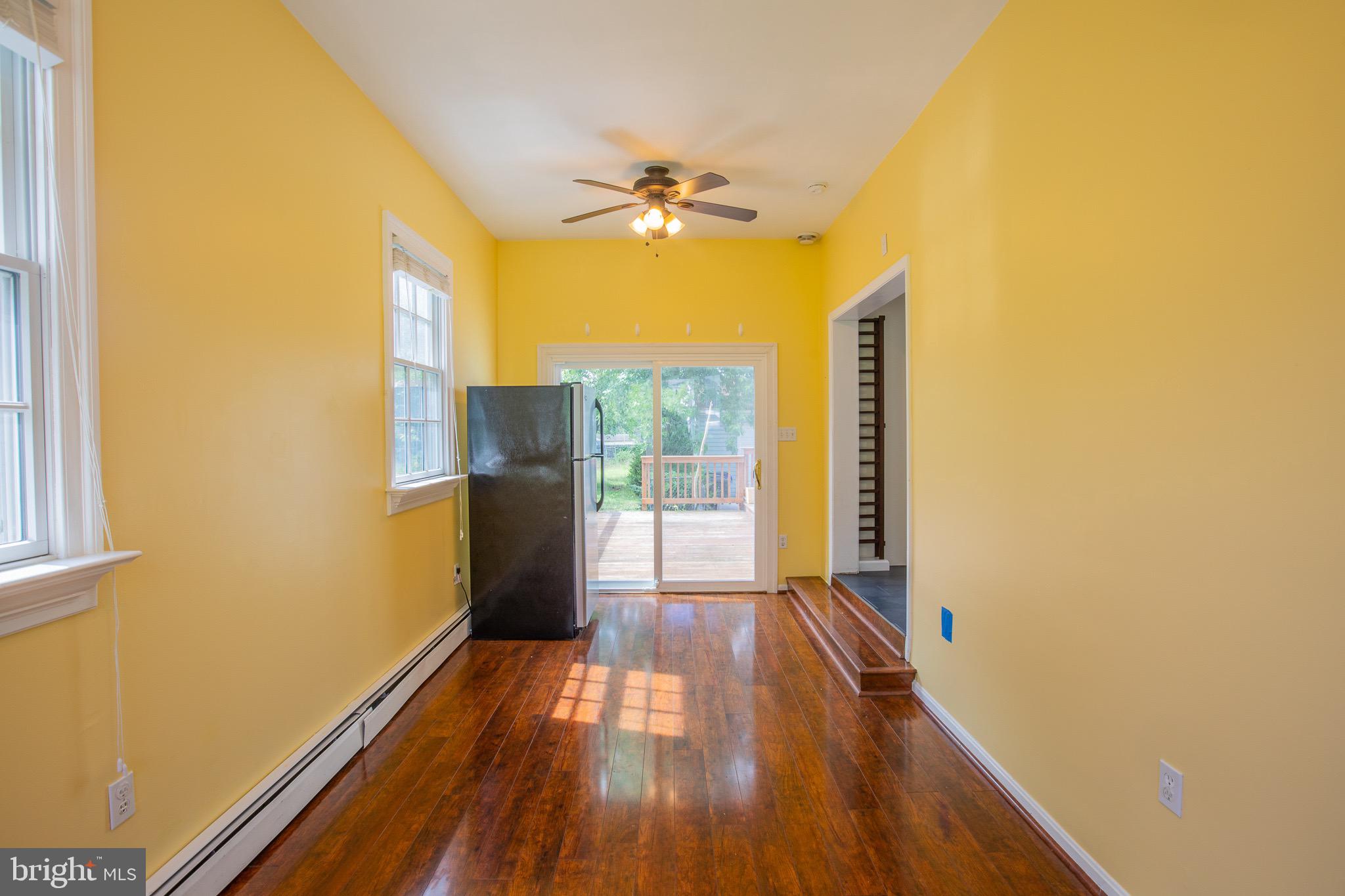 8875 Baltimore Street Savage, MD 20763 - Photo 8 of 32 a view of a room with wooden floor a ceiling fan and windows