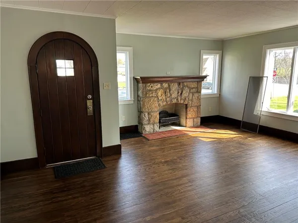 an empty room with wooden floor fireplace and windows