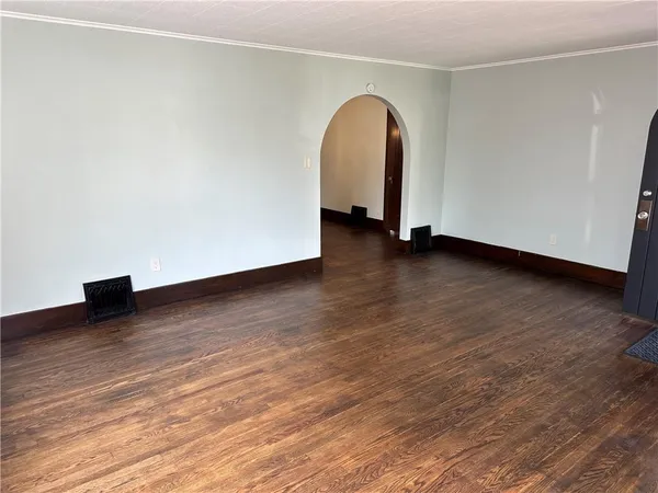 an empty room with wooden floor fireplace and windows