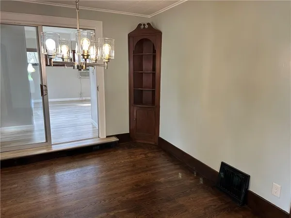an empty room with wooden floor chandelier and windows