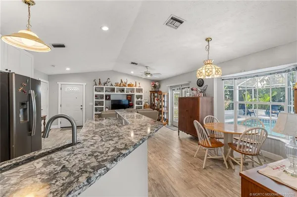 a view of a dining room and livingroom with furniture wooden floor a rug a fireplace and a chandelier