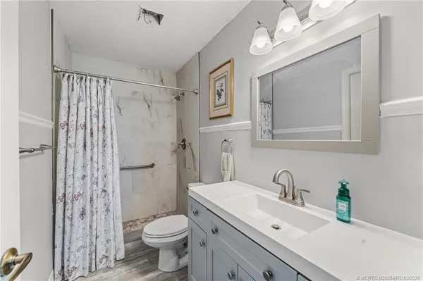 a bathroom with a granite countertop sink toilet a mirror a vanity and shower