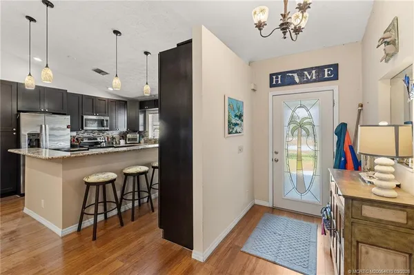 a kitchen with kitchen island stainless steel appliances a stove refrigerator dining table and chairs