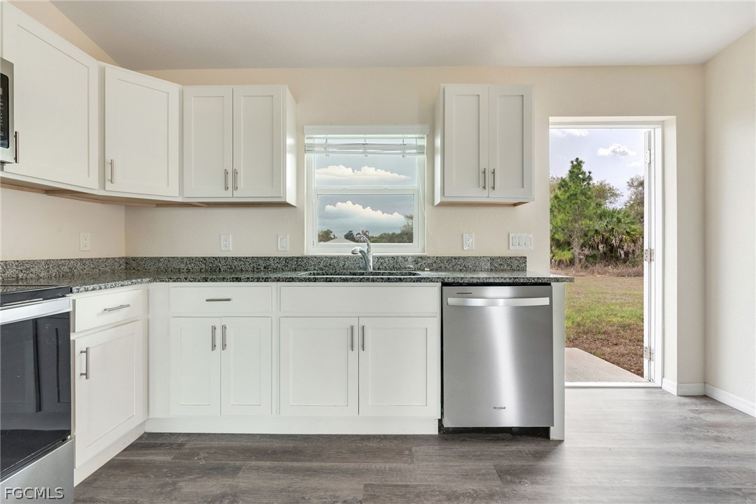 1405 Inwood Road LaBelle, FL 33935 - Photo 5 of 35 a kitchen with granite countertop white cabinets and white appliances