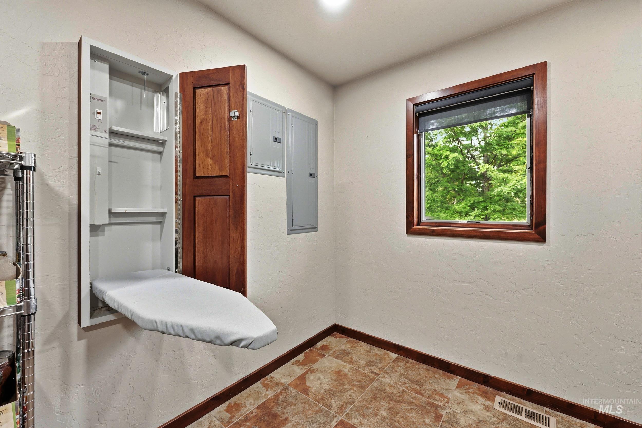 339 Airport Road Weiser, ID 83672 - Photo 20 of 49 Utility room featuring a wall-mounted ironing board, a single window with wood trim, textured white walls, and tiled flooring