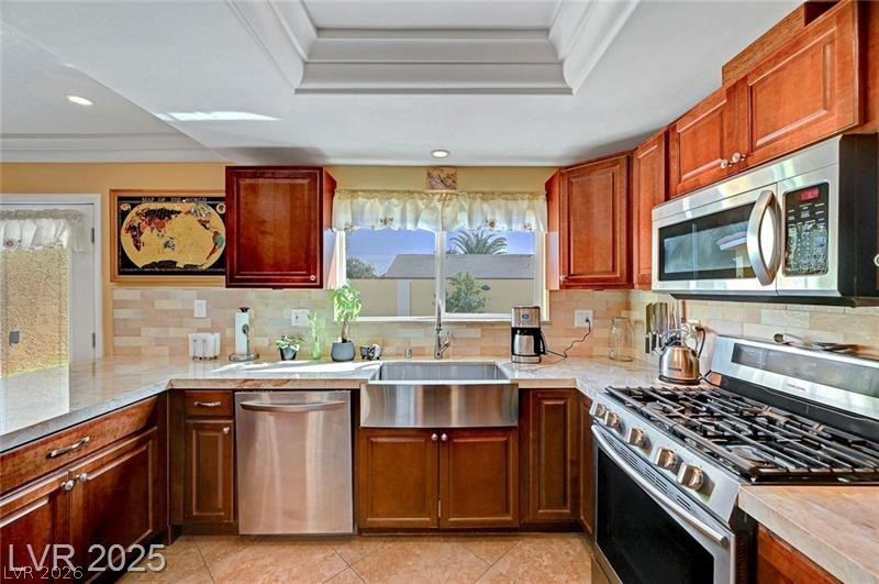 2410 Doherty Way Henderson, NV 89014 - Photo 25 of 63 Kitchen featuring stainless steel appliances, a sink, a raised ceiling, light tile patterned flooring, and crown molding