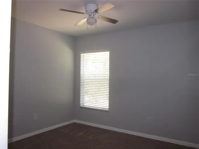 an empty room with a window and a fan