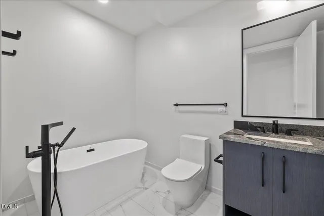 a bathroom with a granite countertop toilet sink and mirror
