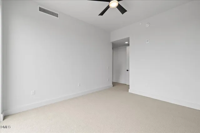 an empty room with a ceiling fan and carpet