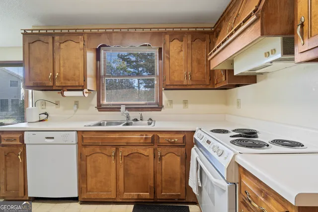 a kitchen with stainless steel appliances granite countertop a refrigerator a sink dishwasher a stove and white countertops with wooden floor