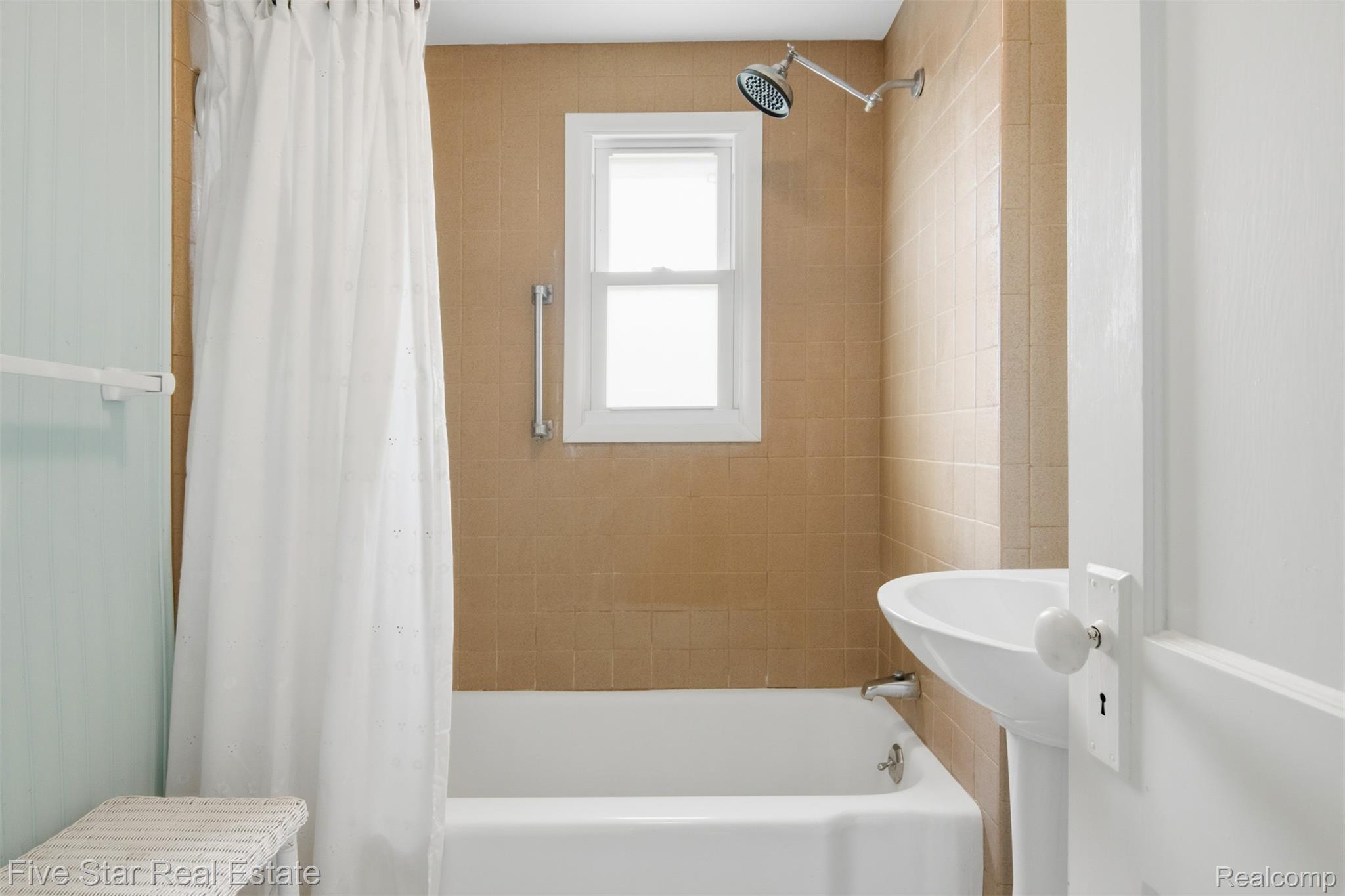 2588 Lakeview Road Onekama, MI 49675 - Photo 23 of 32 Bathroom with a pedestal sink, white bathtub, and shower with a chrome fixture