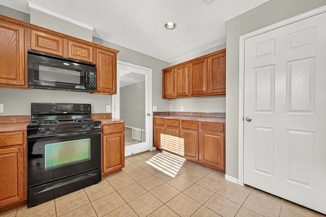a kitchen with granite countertop a stove top oven microwave and cabinets