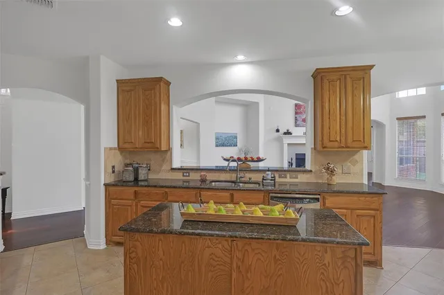 a kitchen with kitchen island granite countertop a sink a counter top space and cabinets